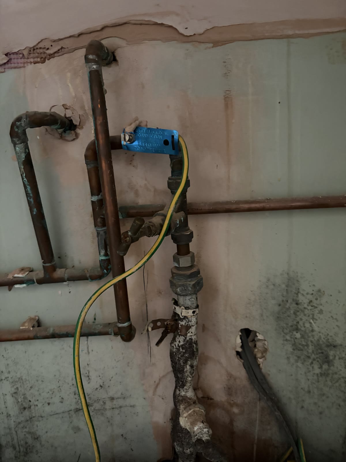 Lead incoming main, stop tap and copper pipework exposed behind a kitchen cupboard during a leak investigation in Blaby